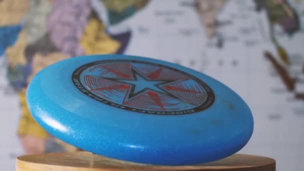 Blue Frisbee Discraft Tegen Een Wazige Wereldkaart Camera Vliegt Rond — Stockvideo