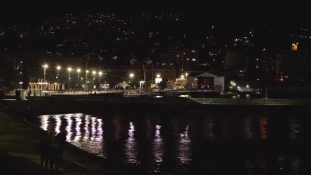 Pessoas Caminham Longo Passeio Noturno Água Mar Reflete Luz Das — Vídeo de Stock