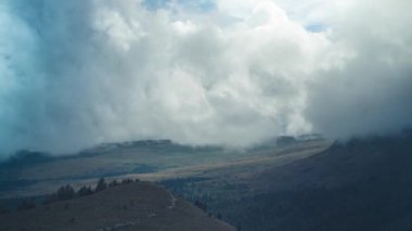 Dağ vadisinde dönen bulutların zamanı. Alçak asılı bir bulut dağların üzerinden geçiyor. Yumuşak kamera yaklaşımı