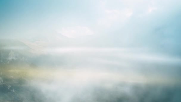 ドローンは山の峡谷を越えて雲の中を飛ぶ 目の前には霧に覆われた雪原のある高い山がある 山のタイムラプス — ストック動画