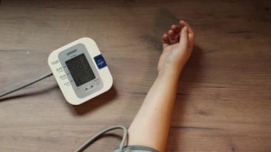 Bir kadın kan basıncını otomatik tonometreyle ölçer. Eli ve cihaz masanın üstünde. Kendi sağlıklarının gözlemlenmesi. Krasnodar, Rusya 12 Eylül 2021