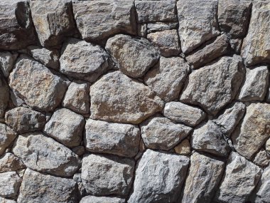 Taşlarla kaplı bir duvar. Gün ışığı. Dış çevre. Outdor.