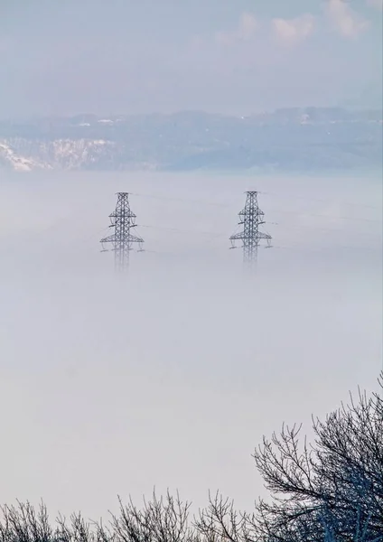 Güç hattı direkleri sisli bir nehrin üzerinde