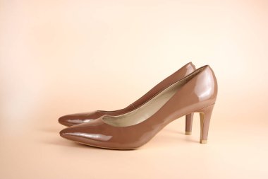 Pembe arka planda kadınların bej renkli deri ayakkabıları.