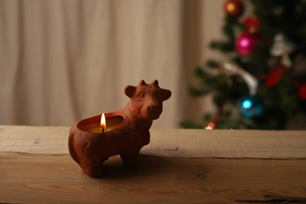 Candela Argilla Forma Mucca Uno Sfondo Legno Contro Albero Natale — Foto Stock