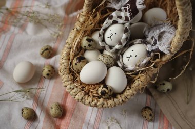 İki Paskalya yumurtası bir sepetin içinde tavşancık şeklinde ve peçetenin üzerinde çiçeklerle süslenmiş yumurtalar. Paskalya konsepti.