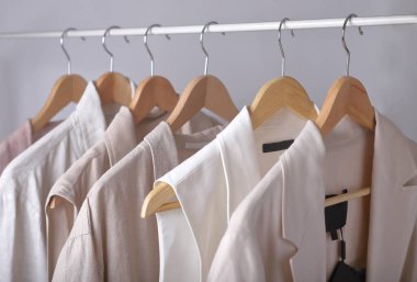 Açık renkli giysiler askıda asılı..