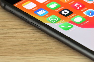 iPhone ekranında bir Whatsapp simgesi, ahşap arka plan