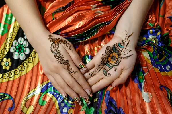 Dvou ženách ruce mehendi obrázek oranžové světlé textilie s záhybů — Stock fotografie
