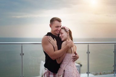 Deniz kenarındaki güzel aşıklar, okyanus manzarası, berrak su, gökyüzü yansıması. Seyahat, yeni tatil, turizm. Parlak gün batımı ya da gün doğumu. Kadın erkeğe yakındır, nazikçe sarılır. Gülümse, sevginin tadını çıkar