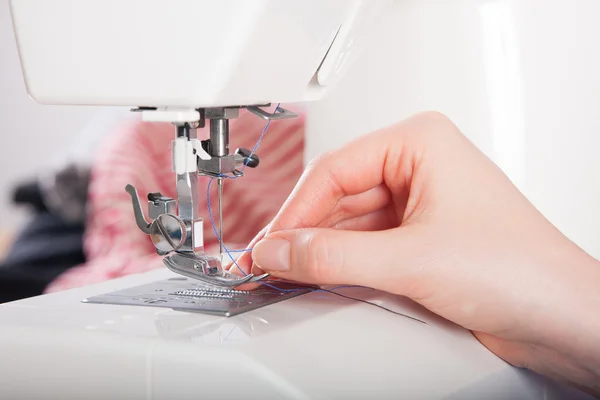 Frau fädelt auf Nähmaschine ein — Stockfoto