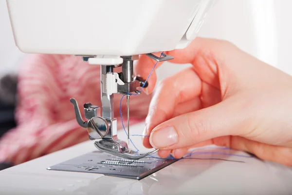 Mujer roscando en la máquina de coser Imagen de archivo