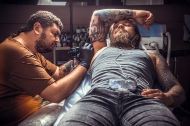 Bir dövme dövme salonunda yapma işlemi gösteren tattooer