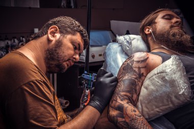 Dövmeci dövmecide dövme yapıyor.