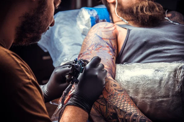 Maestro del tatuaggio al lavoro nel salone del tatuaggio — Foto Stock