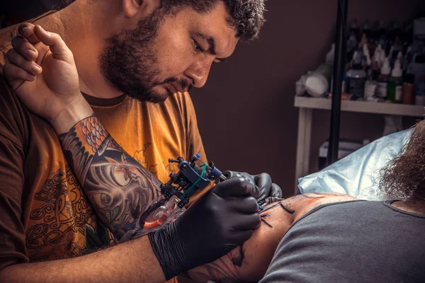 Professional tattooer makes tattoo pictures in tattoo parlor — Stock Photo, Image