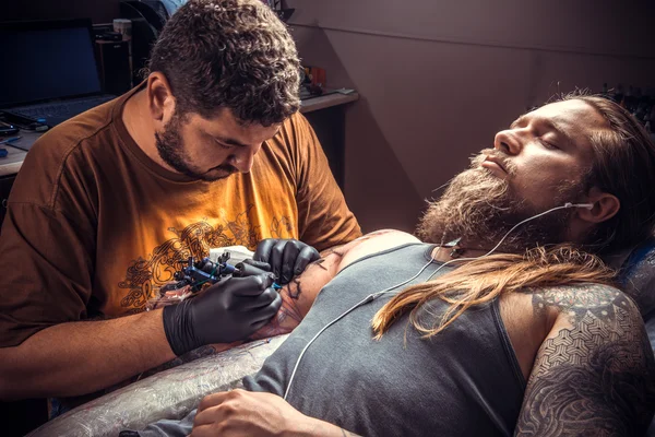 Mestre de tatuagem faz imagens de tatuagem em sala de tatuagem — Fotografia de Stock