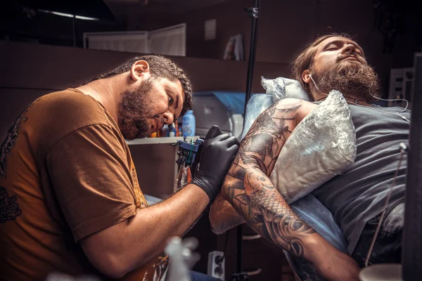 Tattooer робить татуювання в тату-салон — стокове фото