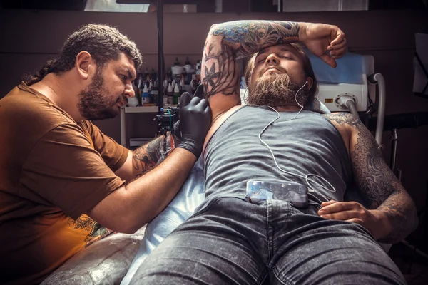 Tattooer visar processen för att göra en tatuering i tatuerare — Stockfoto