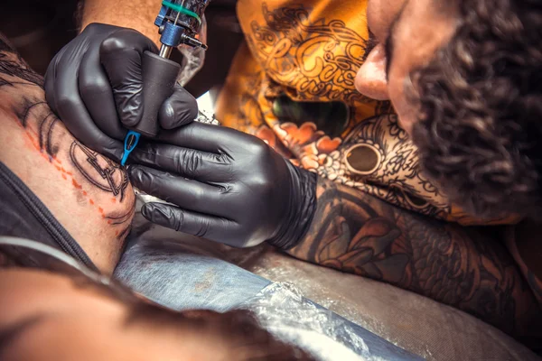 Especialista em tatuagem mostrando processo de fazer uma tatuagem em sala de tatuagem — Fotografia de Stock