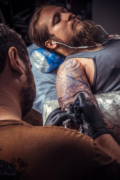 Tatuagem artista mostrando processo de fazer uma tatuagem no salão de tatuagem — Fotografia de Stock
