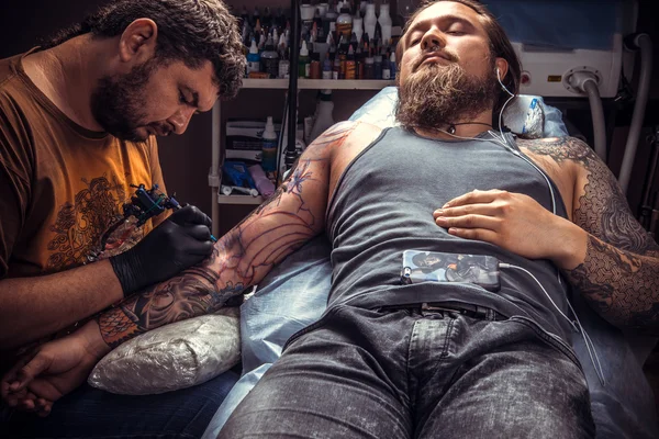 Man bär handskar får tatuering i tatuerare — Stockfoto