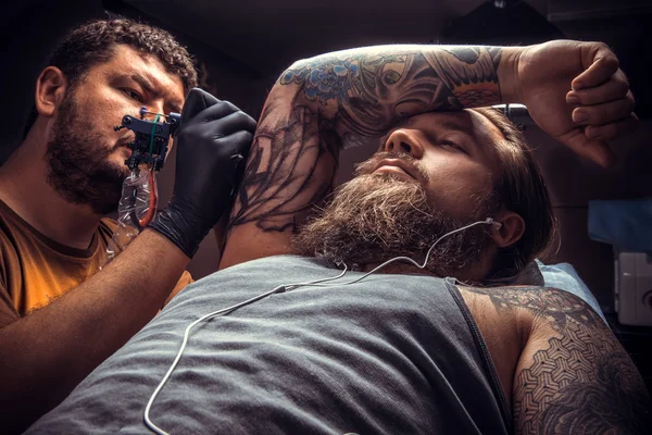 Tattoo master making a tattoo in tattoo parlour — Stock Photo, Image