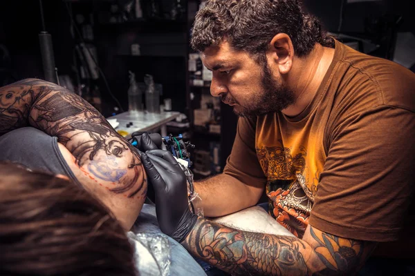 Artista profesional del tatuaje haciendo un tatuaje en el salón de tatuajes — Foto de Stock