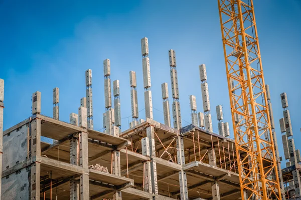 Staveniště s jeřábem a nedokončený cbuilding s modrou oblohou — Stock fotografie