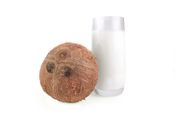 Coco entero y leche en un vaso sobre fondo blanco aislado — Foto de Stock