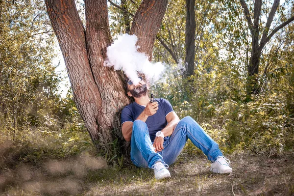 Tarz sahibi bir adam e-sigara içer ve duman bulutu solur. Vape. — Stok fotoğraf