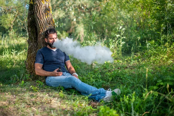 Fumatore barbuto all'aria aperta fumare un dispositivo di fumo elettronico. Vaporizzatore. — Foto Stock