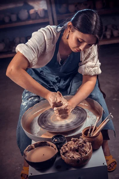 Encantadora mulher mestre oleiro trabalha com argila em uma roda oleiros. Trabalho manual. — Fotografia de Stock