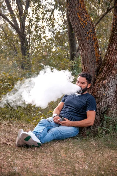 Fumatore moderno soffia un sacco di fumo utilizzando sigaretta elettronica vaporizzatore. Vaporizzazioni. — Foto Stock