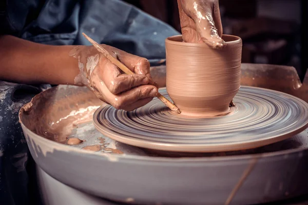 O mestre-ceramista cria um pote de barro em uma roda de oleiros. Mãos de oleiro de perto. Artesanato antigo e trabalho artesanal de cerâmica — Fotografia de Stock