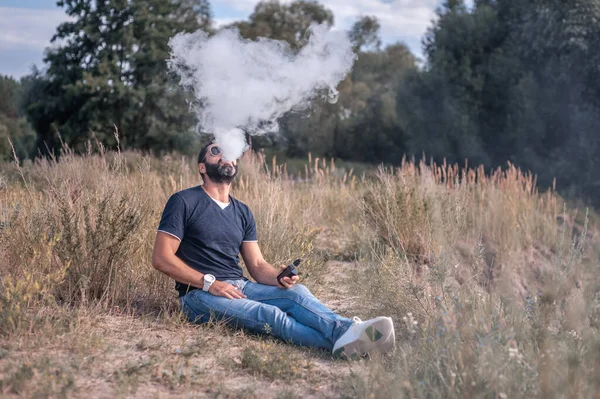 Bello vaporizzatore che si gode un dispositivo elettronico di fumo sull'erba. Non fumatori di tabacco. — Foto Stock