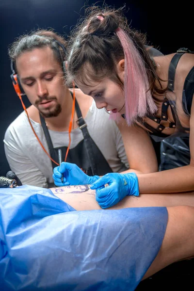 Master tattooist demonstrates the process of getting tattoo in tattoo parlor — Stock Photo, Image