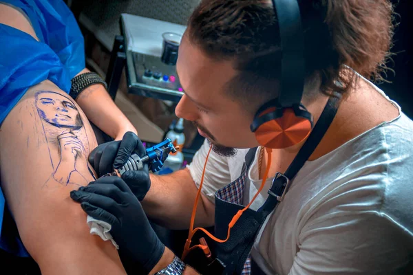 Master of the art of tattooing makes a tattoo on the clients tattoo studio — Stock Photo, Image