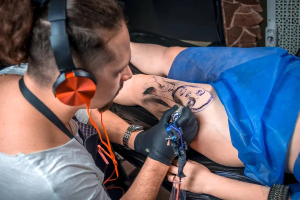 Professionell tatuerare som arbetar på professionell tatuering maskin enhet i tatuering studio — Stockfoto