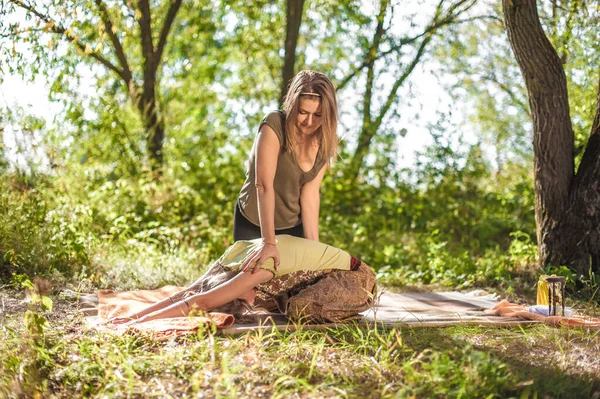 Maestro masaje thuroughly masajes a una chica en el suelo del bosque. —  Fotos de Stock