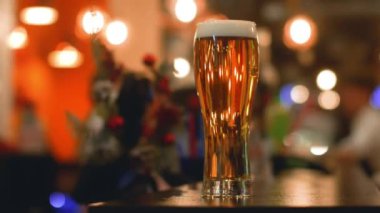Bar tezgahında bir bardak light bira var.