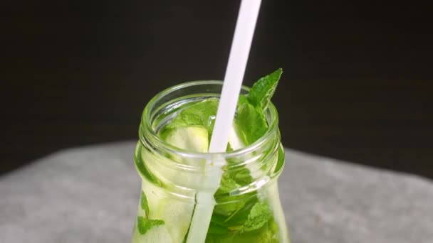 Gros plan du goulot d'étranglement avec mojito, paille, feuilles de menthe et tranches de lime — Video