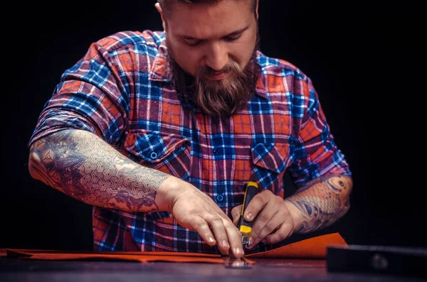 Deri ustası deri eşyalarıyla deri atölyesinde konuşuyor.