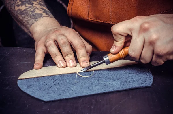 Professional Leather Worker focused on his work in a workshop
