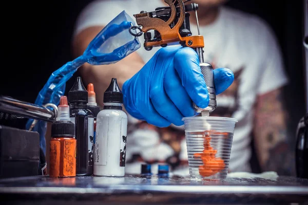 Mão de um tatuador, segurando uma arma de tatuagem. — Fotografia de Stock