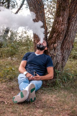 Temiz havada elektronik sigara içen şık bir viyak 'a. Buhar etkinliği.