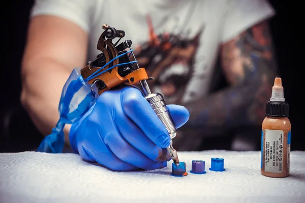 Tetoválógéppel felszerelt tetováló művész keze. — Stock Fotó