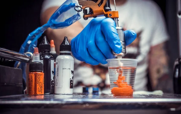 Hand of a tattoo master and a tattoo gun. — Stock Photo, Image