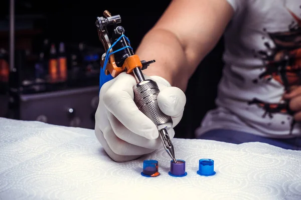 Hand of a tattoo master and a tattoo machine. — Stock Photo, Image