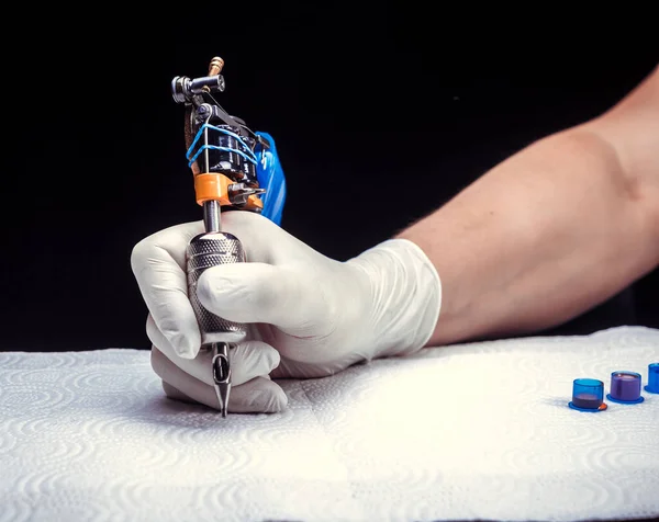 Hand of a professional tattooer and a tattoo machine. — Stock Photo, Image
